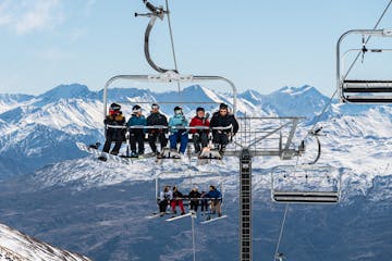a group of people riding a ski lift on top of a snow covered mountain