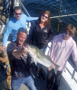 a group of people standing next to a person holding a fish
