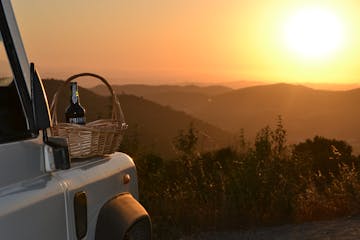 a bottle of wine on a basket with a sunset in the background