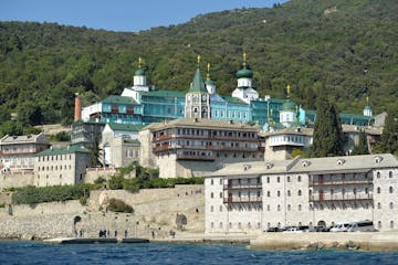 a large ship in a body of water with Mount Athos in the background