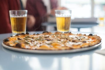 a plate of pizza and a glass of beer on a table