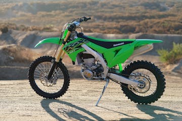 a green motorcycle parked on a dirt road