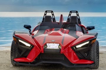 a polaris slingshot parked next to the sea