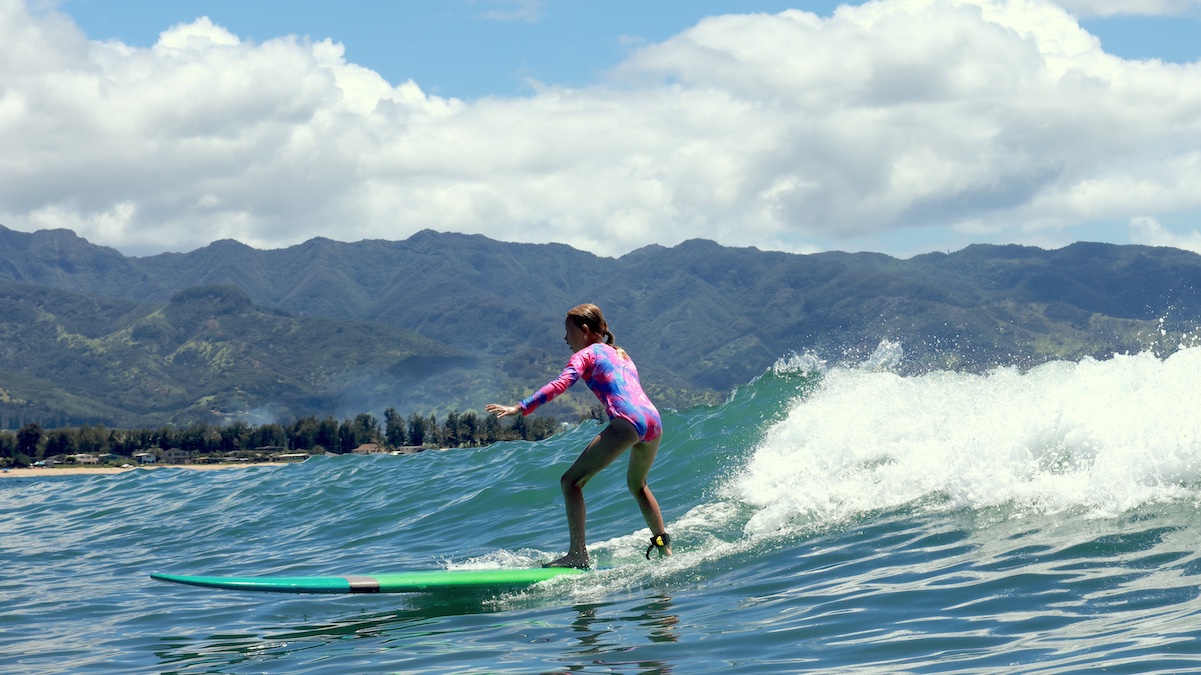 a girl riding a wave on a surf board on a body of water
