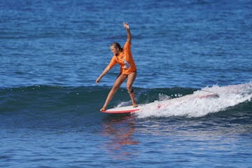 a young girl riding a wave on a surfboard in the water