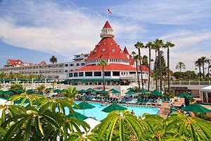 a group of palm trees and buildings in the background with Hotel del Coronado in the background
