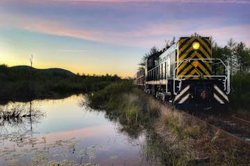 a train traveling down tracks next to a body of water