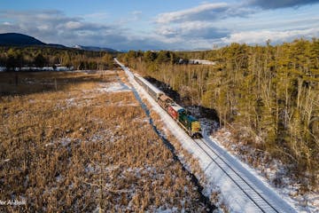 a train is on the side of a snow covered field