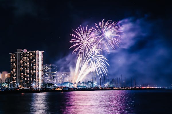 fireworks over a body of water with a city in the background