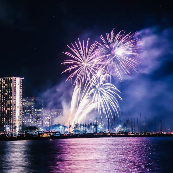fireworks over a body of water with a city in the background