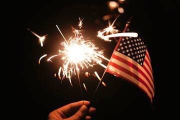 a person that is lit up at night with American flag