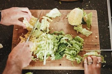 a person slicing vegetable on a cutting board