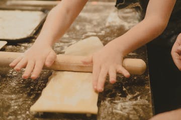 a person flattening a dough using a rolling pin