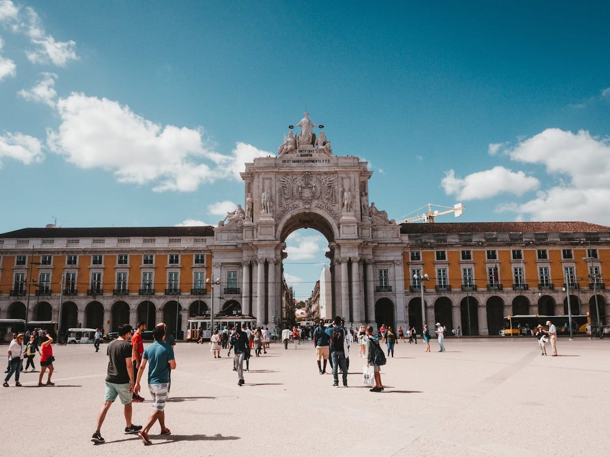 a group of people walking in front of a large building with Praça do Comércio in the background