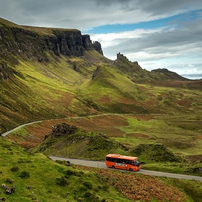The Hairy Coo coach on Skye with the Quiraing in the background