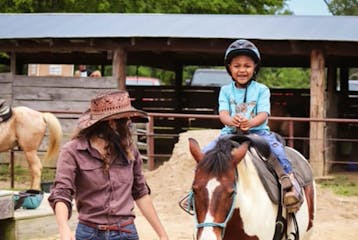 a woman guiding a kid horseback riding at the stables at cedars of lebanon in nashville tn