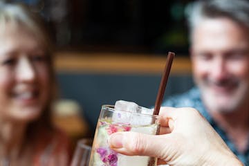 beautiful cocktail with flowers, and two happy people in the background
