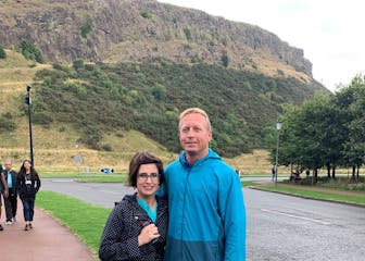 a man and a woman standing in front of a mountain