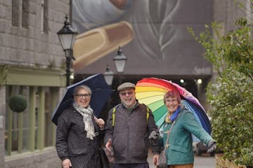 a man and a woman walking down a street holding an umbrella