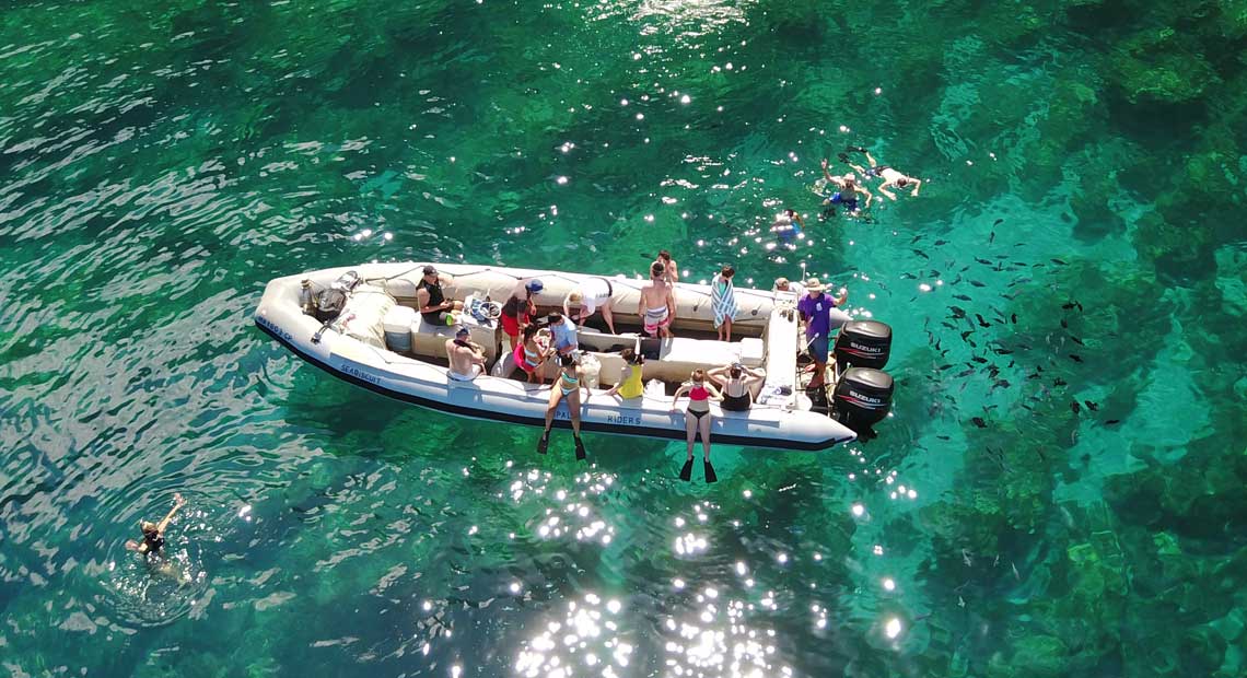 People Snorkeling with fish over a reef in Kauai on a Na Pali Coast Boat Tour