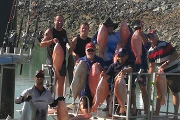 a group of men posing for the camera holding up the fishes they caught on a full day fishing charter with airlie beach fishing charters in airlie beach, queensland
