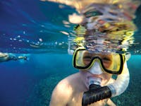 a man wearing sunglasses taking a selfie in a body of water