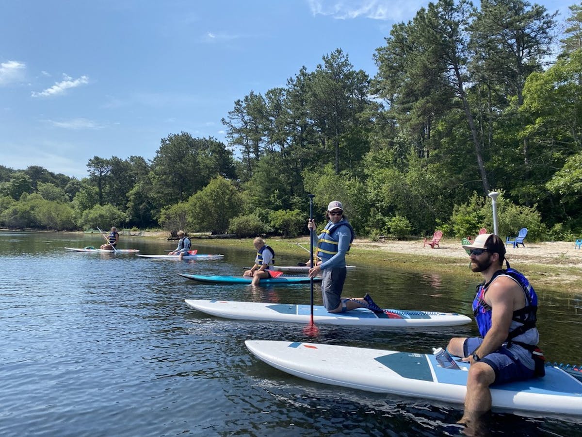 A group vacationing on Cape Cod books paddle board and kayak rentals with Rideaway Adventures at Lawrence Pond in Sandwich, MA