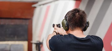 man directs firearm at target shooting range