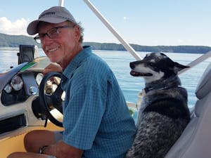 a man sitting on a boat with a dog