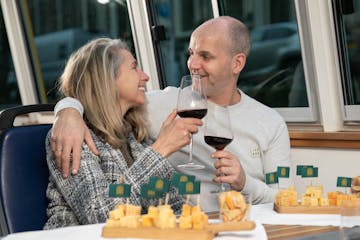 a man and a woman sitting at a table eating cheese