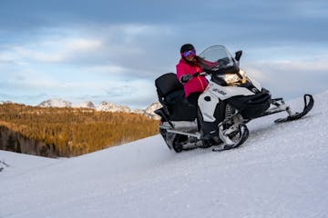 a woman riding a snowmobile down a snow covered slope