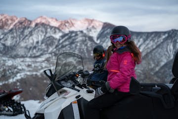 two people sitting on snowmobiles