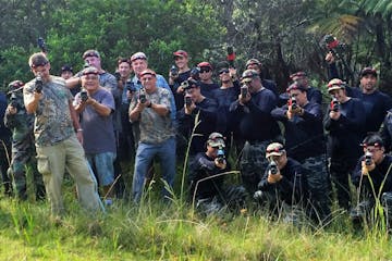 A group of people decked out in camouflage and black holding up laser tag guns in a cloud forest in Hawaii