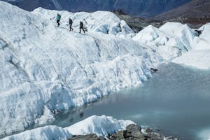 three people walking across a glacier