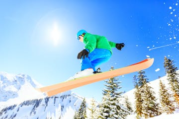 a man flying through the air while riding a snow board