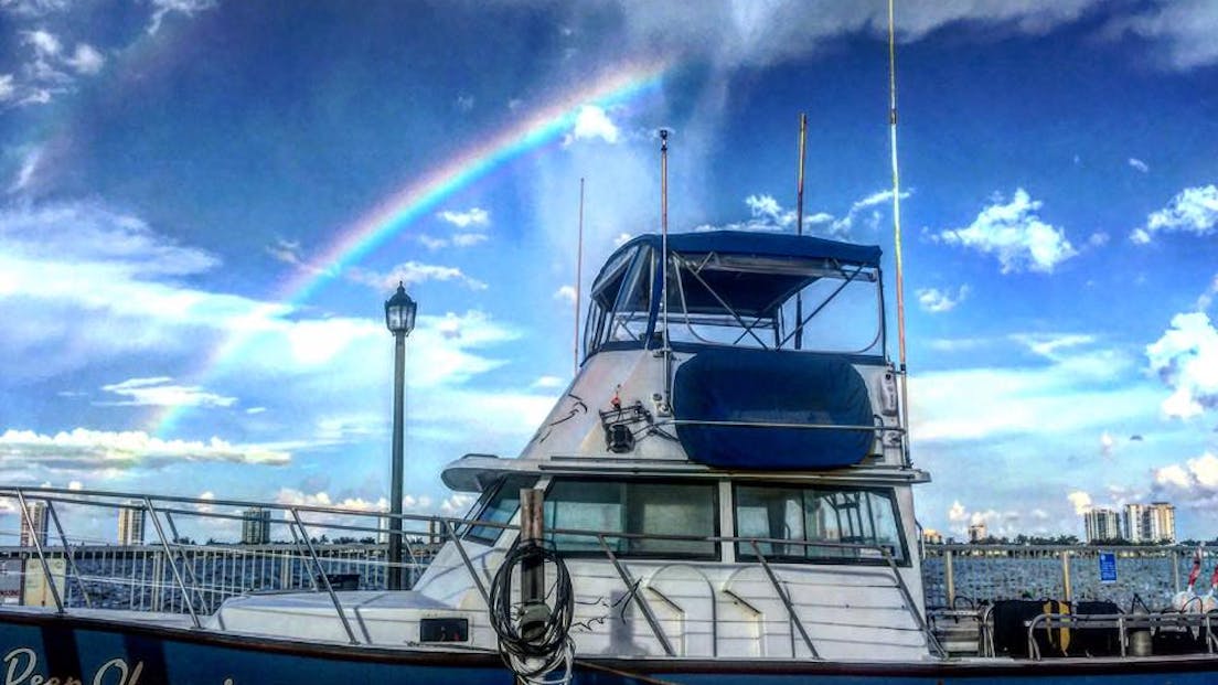 deep obsession boat with rainbow in the background