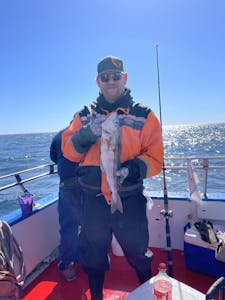 a person holding a fish on a boat posing for the camera