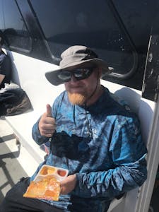 a man wearing a hat and sunglasses sitting on a boat