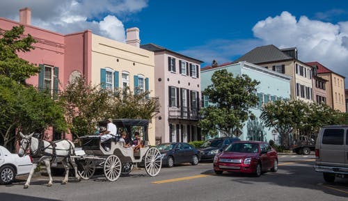 self-guided walking tour of charleston: a person riding a horse drawn carriage on a city street