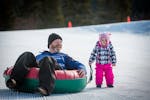 A father and daughter tubing on a snow tube