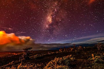 milky way fills the sky over active lava fields