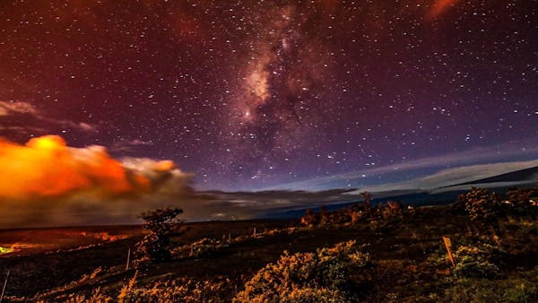 milky way fills the sky over active lava fields