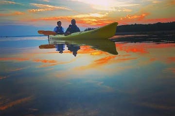 two people in a tandem kayak enjoying a sunset on the water